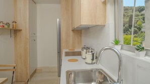 Una cucina compatta con mobili in legno, un lavandino in acciaio inossidabile e una finestra vista verde.