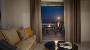 Un accogliente soggiorno con divano e tavolino, un balcone con tavolo e sedie, e vista sul cielo notturno.