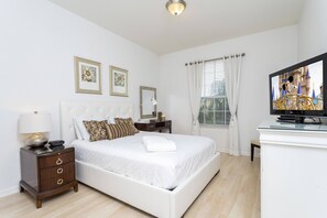 A bedroom with a bed, a nightstand, a TV, and a window with curtains. - Last Minute Disney Getaway! Luxury Condo with Private Balcony. Book Now! #40457 (Orlando)