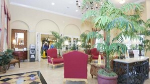 Eine Lobby mit roten Sesseln, einer Rezeption und großen Topfpflanzen.