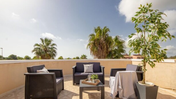 A rooftop terrace with wicker furniture, a small table, and a potted plant. - Antonella by Interhome (Deltebre)