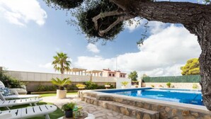 A poolside area with lounge chairs, a stone pool, and a view of a residential building. - Antonella by Interhome (Deltebre)