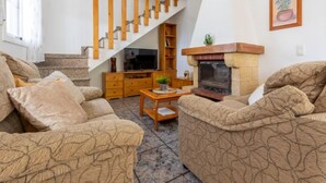 A living room with a fireplace, wooden staircase, and a television. - Antonella by Interhome (Deltebre)