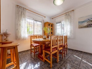 Un coin repas avec une table ronde en bois et des chaises, un buffet en bois et un tableau accroché au mur.