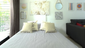 Una habitación de hotel con una cama, un sofá y un amplio ventanal con cortinas.