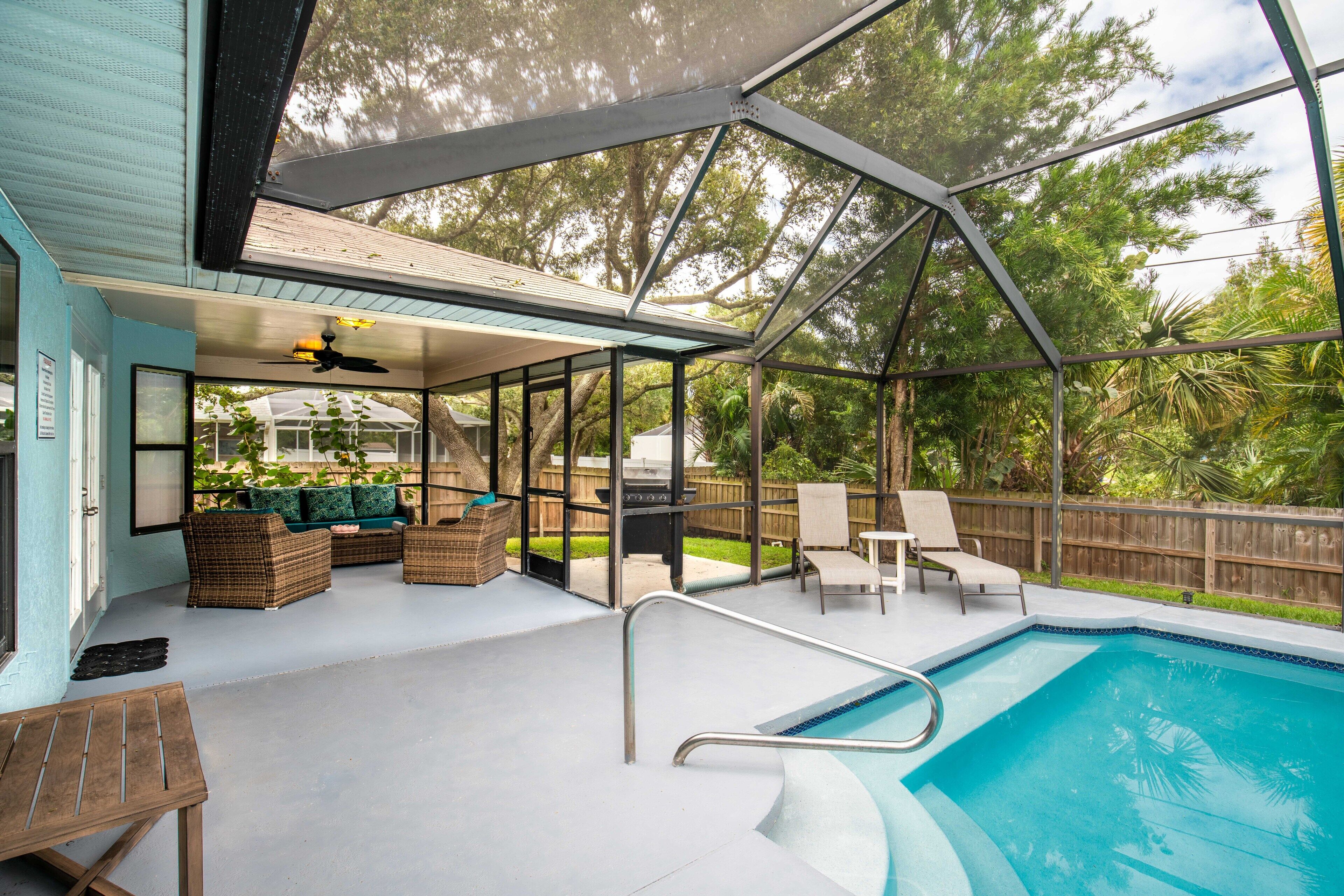 Un espace piscine extérieur abrité, doté d’une terrasse, de sièges et offrant une vue sur le jardin arrière.