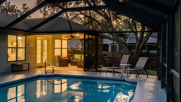 A covered outdoor swimming pool with lounge chairs, a patio area, and a view of the backyard. - Pet Friendly! Huge Heated Pool Quiet Neighborhood Close to Beach Gr8 4 Families! (Sebastian)