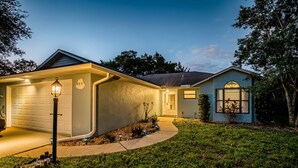 A residential house with a garage, a well-lit front yard, and a small garden area. - Pet Friendly! Huge Heated Pool Quiet Neighborhood Close to Beach Gr8 4 Families! (Sebastian)