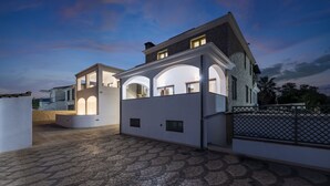 A modern house with a spacious patio area, a covered outdoor seating area, and a well-lit entrance. - Arbatax Sa Omu Bianca (Tortoli)