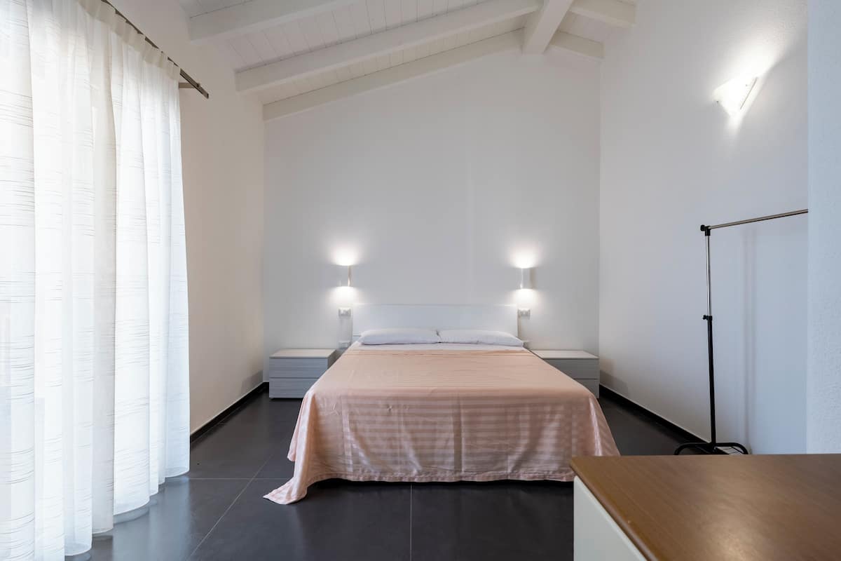 Une chambre à coucher au style minimaliste, avec un grand lit, deux lampes de chevet et une lampe sur pied.