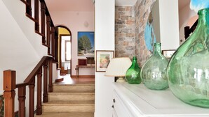 A staircase with wooden railings leading to a room with a white dresser and green glass bottles. - Arbatax Sa Omu Bianca (Tortoli)
