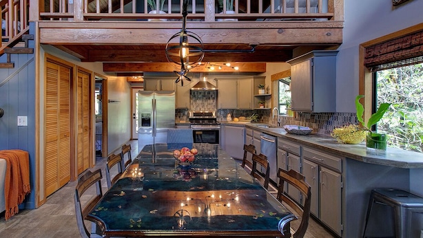 A spacious dining area with a long table, wooden chairs, and a central chandelier. - Halehikiola: 1  BR, 2  BA House in Volcano, Sleeps 6 (Volcano)