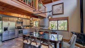 A spacious kitchen with a large island, wooden ceiling, and a view of the outdoors through a window. - Halehikiola: 1  BR, 2  BA House in Volcano, Sleeps 6 (Volcano)