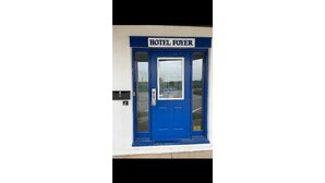 Une porte bleue avec une enseigne indiquant « HÔTEL FOYER » et une fenêtre donnant sur un paysage.