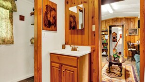 A wooden interior with a white sink, wooden cabinets, a mirror, and a dining area with a table and chairs.