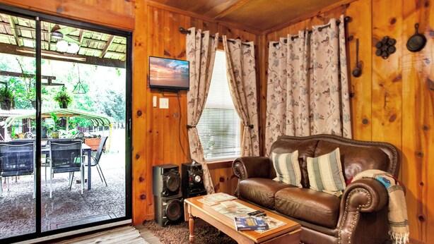 A wooden interior with a leather sofa, a coffee table, and a TV on the wall.