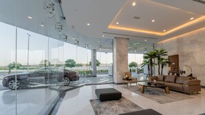 A modern interior with a glass wall, a sofa, a coffee table, and a view of a car outside. - GLOBALSTAY. New Apartments in Business Bay (Dubai)