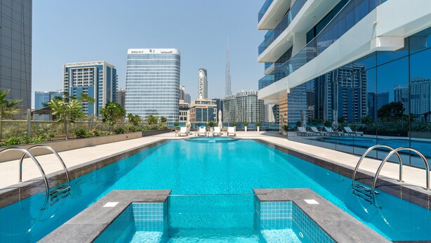 A swimming pool with a cityscape view, including modern buildings and a tall skyscraper. - GLOBALSTAY. New Apartments in Business Bay (Dubai)
