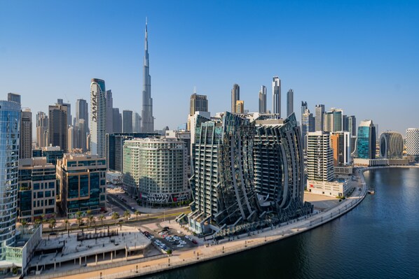 A modern cityscape with high-rise buildings, including a prominent skyscraper, along a waterfront.