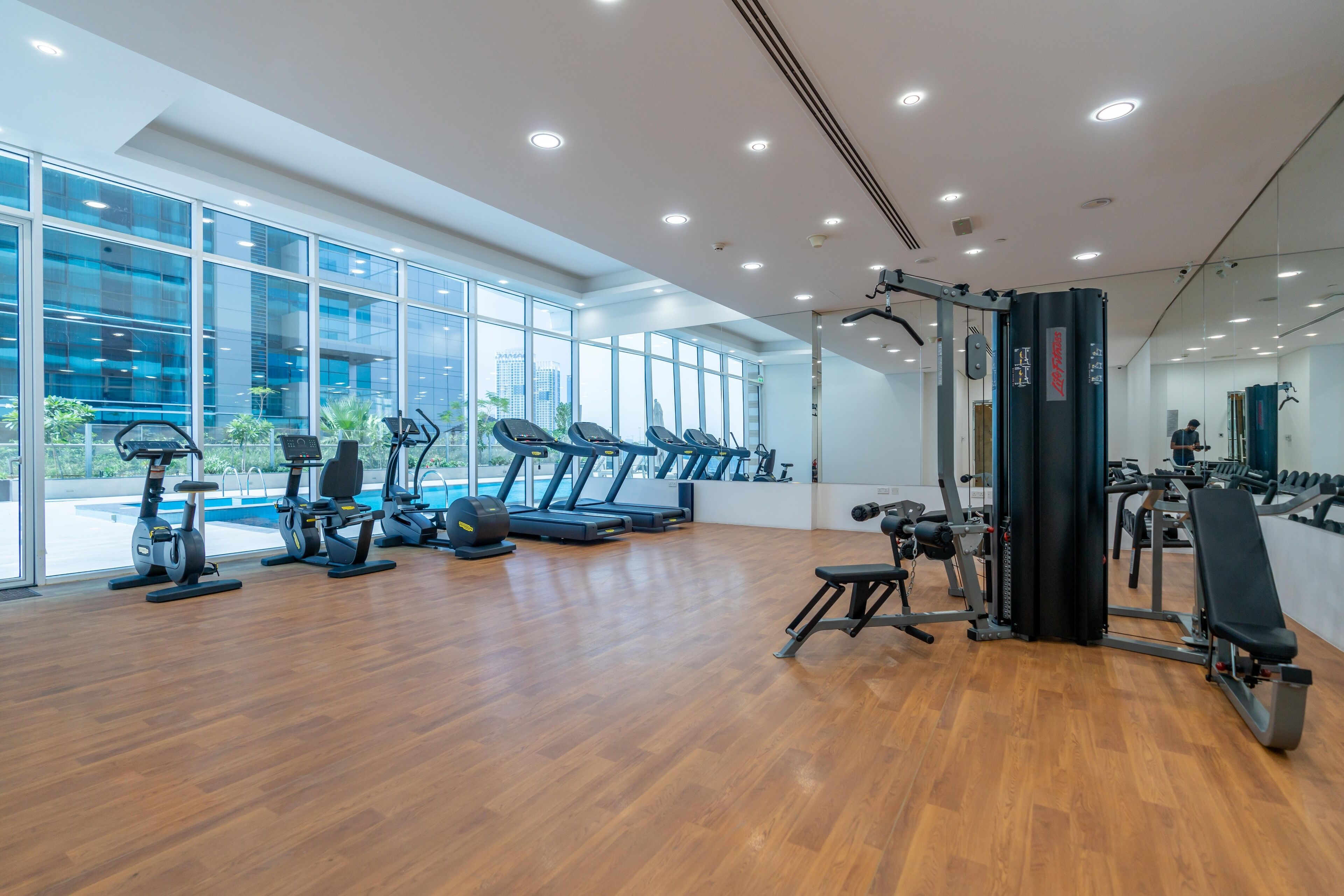 Et moderne fitnesscenter med træningsudstyr, store vinduer og trægulv.