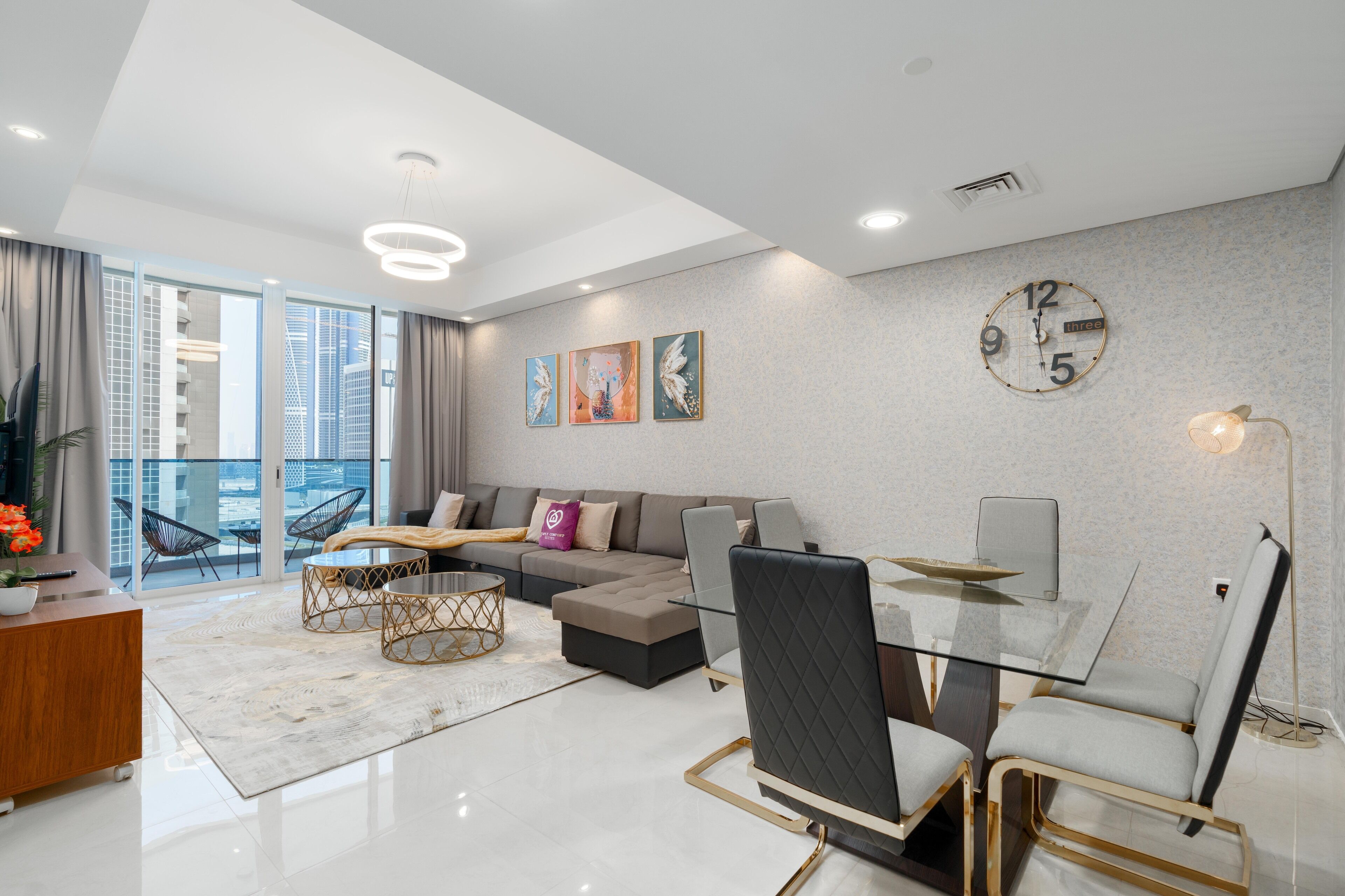 A modern living room with a glass dining table, a sofa, and a large window offering a city view.