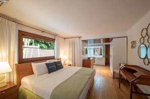 Une chambre d’hôtel avec un lit, des tables de chevet, un bureau et une vue sur l’extérieur.