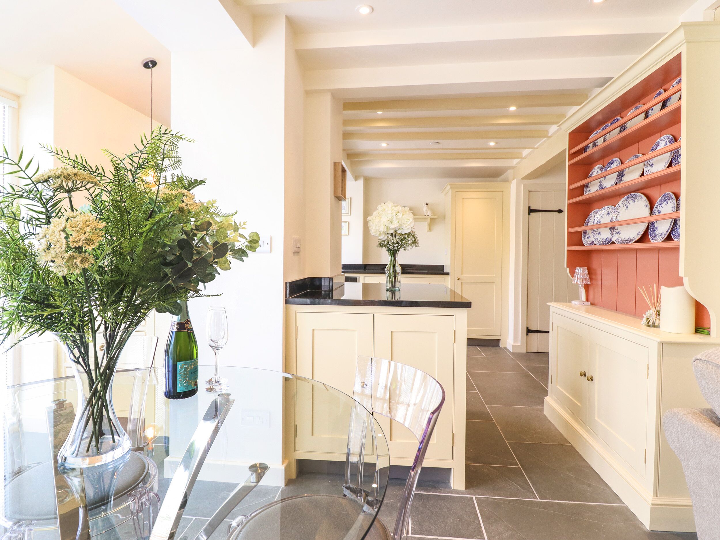A modern kitchen with a central island, a dining area with a glass table, and a display of decorative plates.