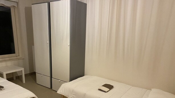 A small, clean room with a single bed, a desk, and a wardrobe.