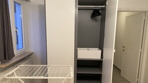 A walk-in closet with a drying rack, shelves, and a door leading to another room.