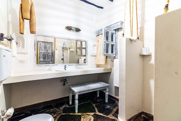 A bathroom with a white sink, a mirror, a towel rack, and a bench. - JUMBO CLUB WATAMU (Watamu)