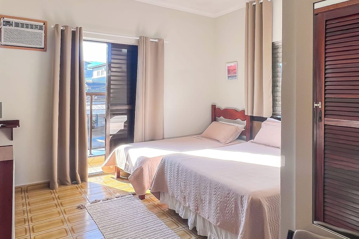 A hotel room with a bed, a chair, a desk, and a window with curtains.