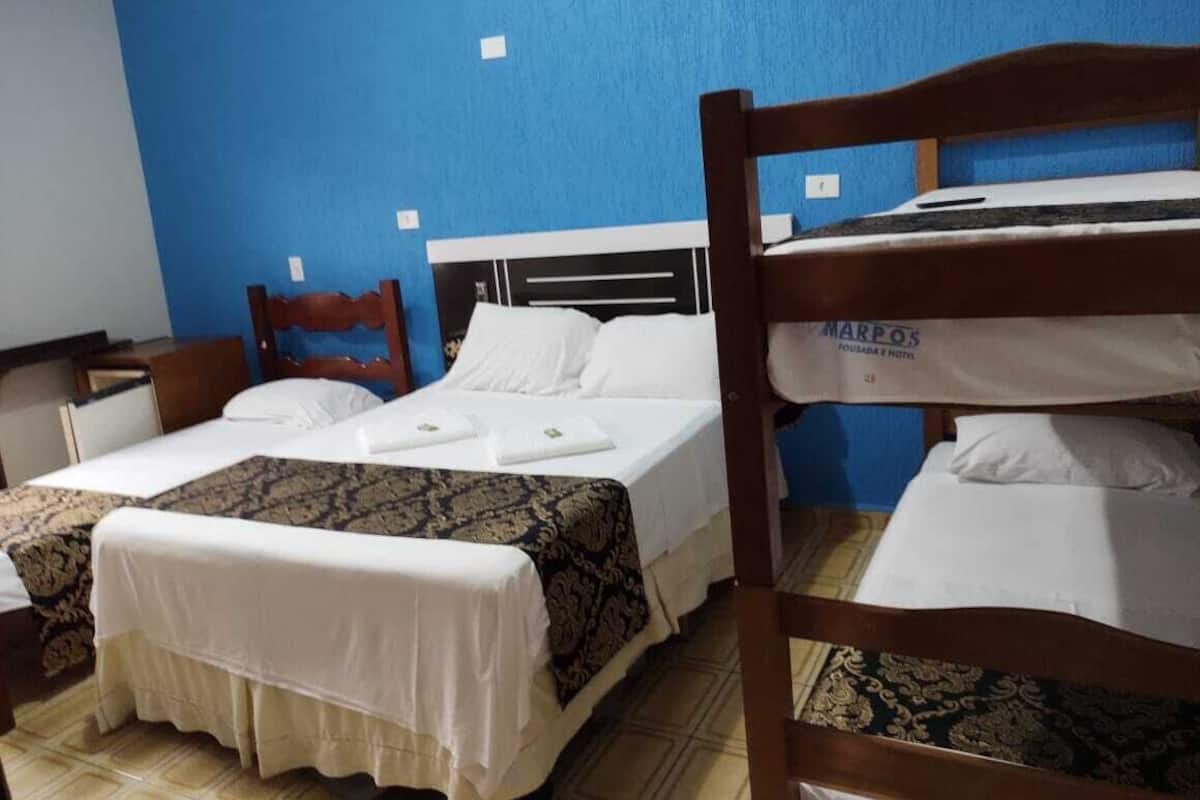 A hotel room with two single beds, a wooden headboard, a desk, and a chair.