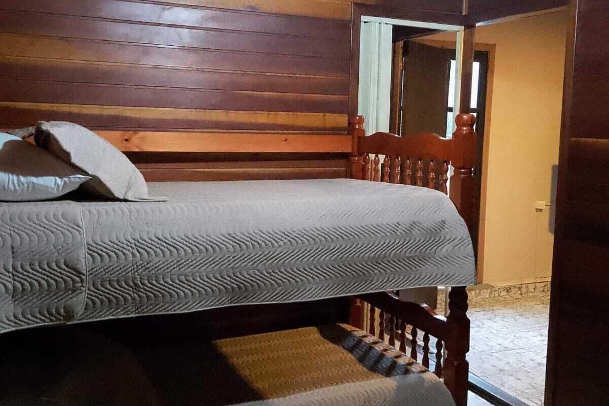 A bunk bed in a room with wooden walls and a sloped ceiling.