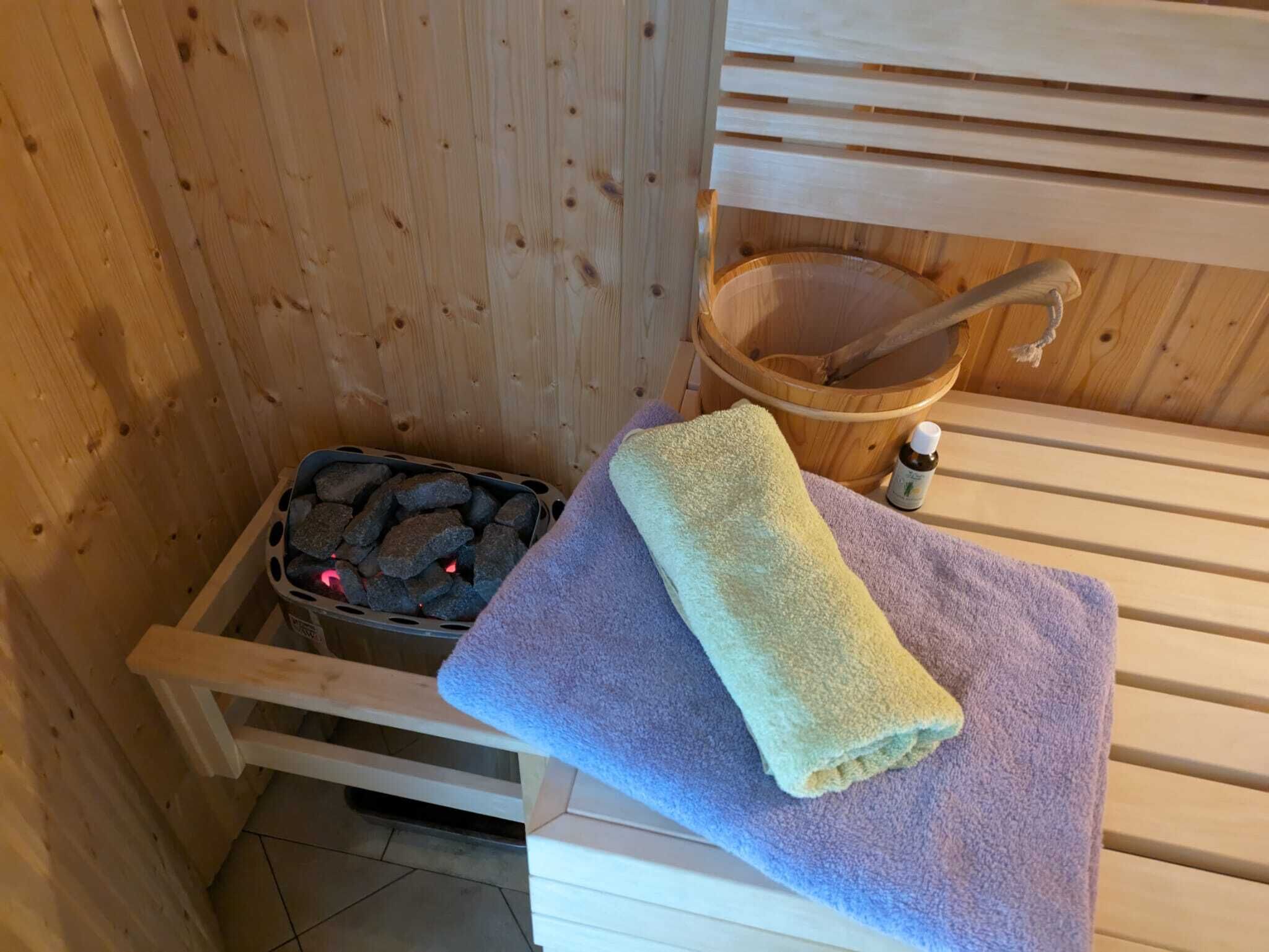 Un sauna avec un banc en bois, un seau et une serviette.