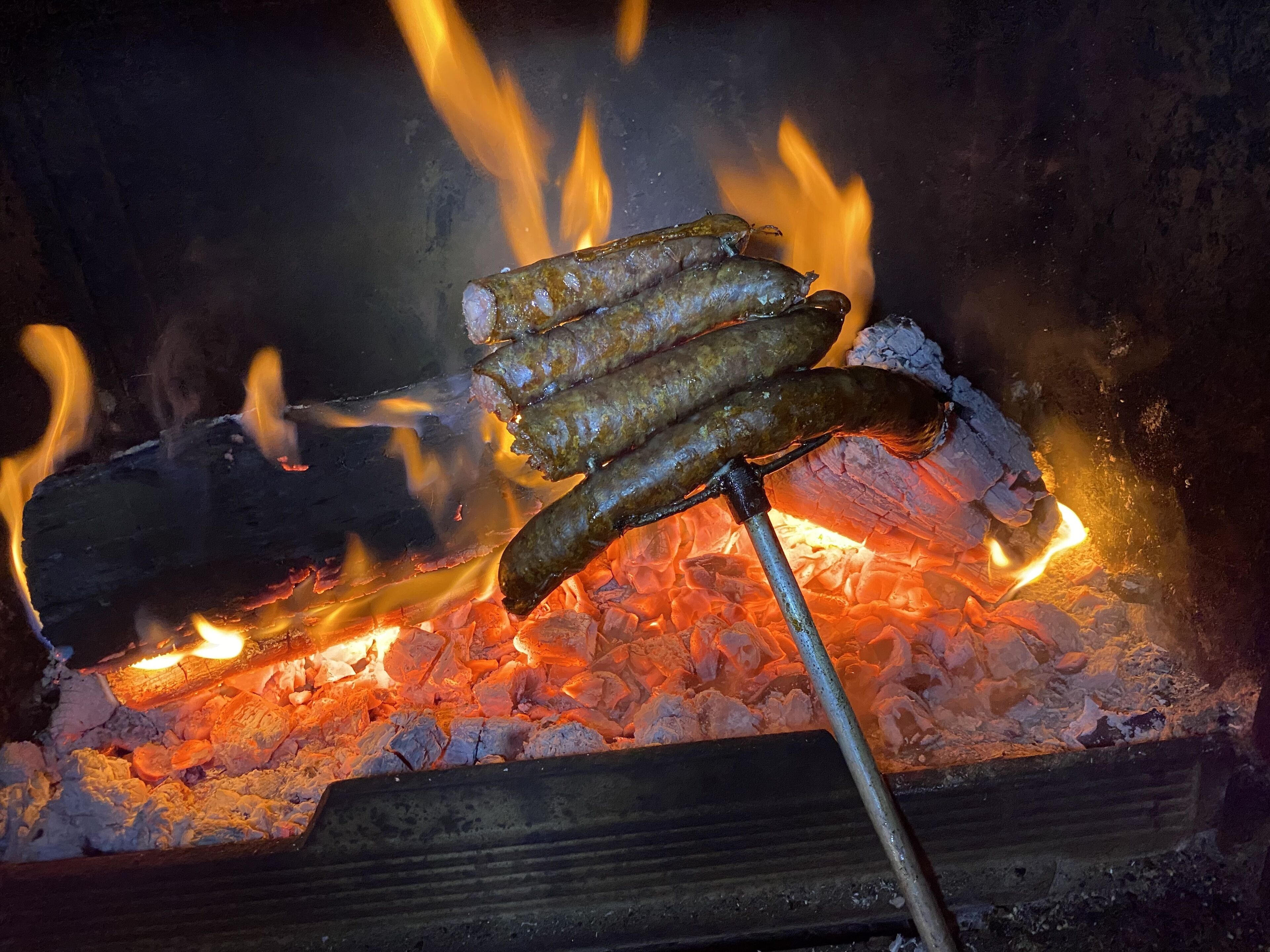 Sausages being grilled over an open fire.