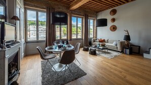 A spacious living area with a fireplace, dining table, and seating. Large windows offer views of the city. - LE LOFT ETHNIC - Grand Studio avec magnifique vue (Lyon)