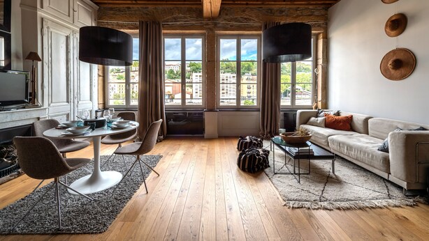 A modern living room with wooden flooring, a round dining table, and a sofa. - LE LOFT ETHNIC - Grand Studio avec magnifique vue (Lyon)