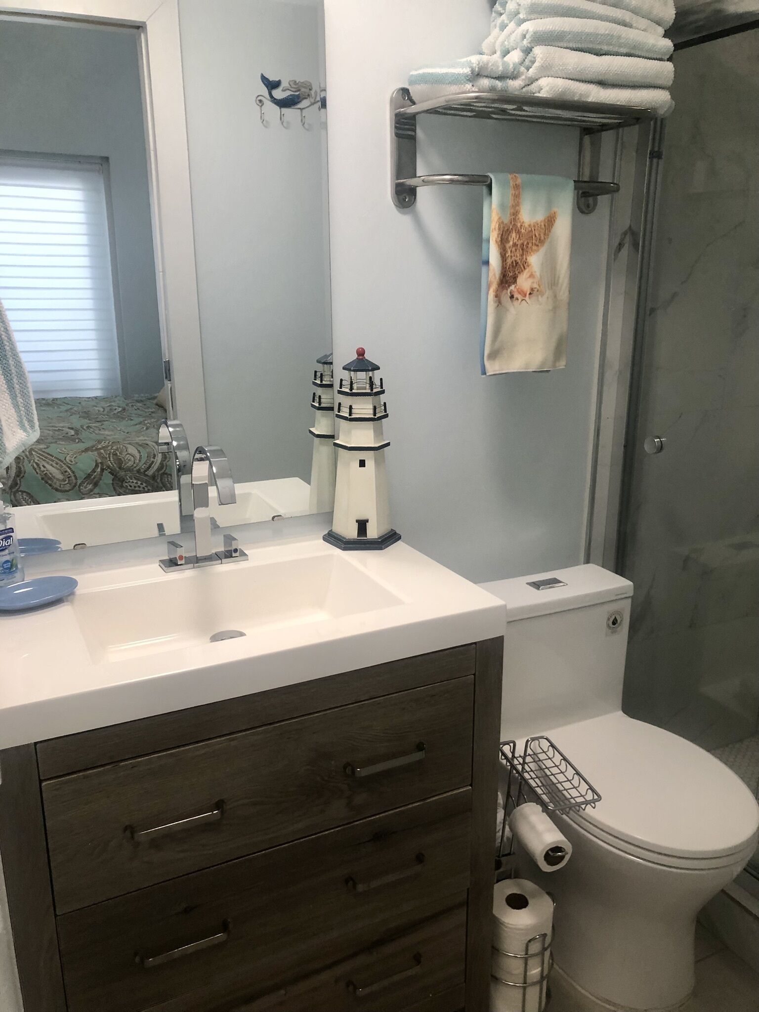 A bathroom with a white sink, dark wooden vanity, a toilet, and a towel rack with folded towels.