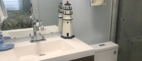 A bathroom with a white sink, dark wooden vanity, a toilet, and a towel rack with folded towels.
