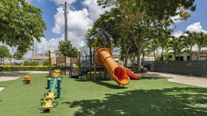 Ein Spielplatz mit Rutsche, Klettergeräten und einem umzäunten Bereich.