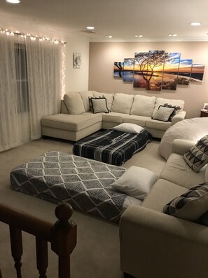 Een woonkamer met een modulaire bank, een gestreept hock en een schilderij aan de muur.