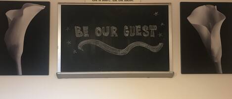 A wall with a sign reading "MOM'S KITCHEN" and a chalkboard with "BE OUR GUEST" written on it.