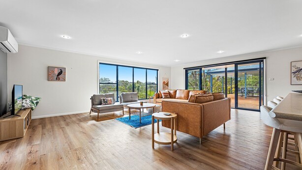 A spacious living area with a large window, a sofa, a coffee table, and a TV. - Blue Haven, North Narooma (North Narooma)
