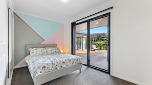 A bedroom with a bed, a view of a deck, and a staircase leading outside.