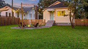 Uma casa com um quintal que inclui uma lareira, área de estar externa e luzinhas.