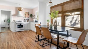 Uma cozinha moderna com armários brancos, piso de madeira e um espaço de refeições com mesa e cadeiras.