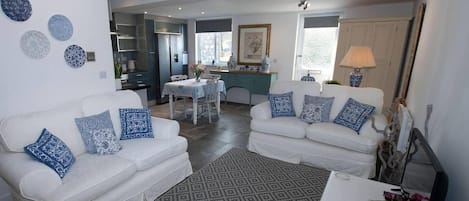 A modern living room with two white sofas adorned with blue patterned cushions, a patterned rug, and a white coffee table.