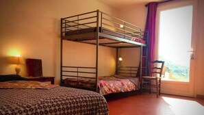 A bunk bed room with a desk and chair, a lamp, and a window with curtains.