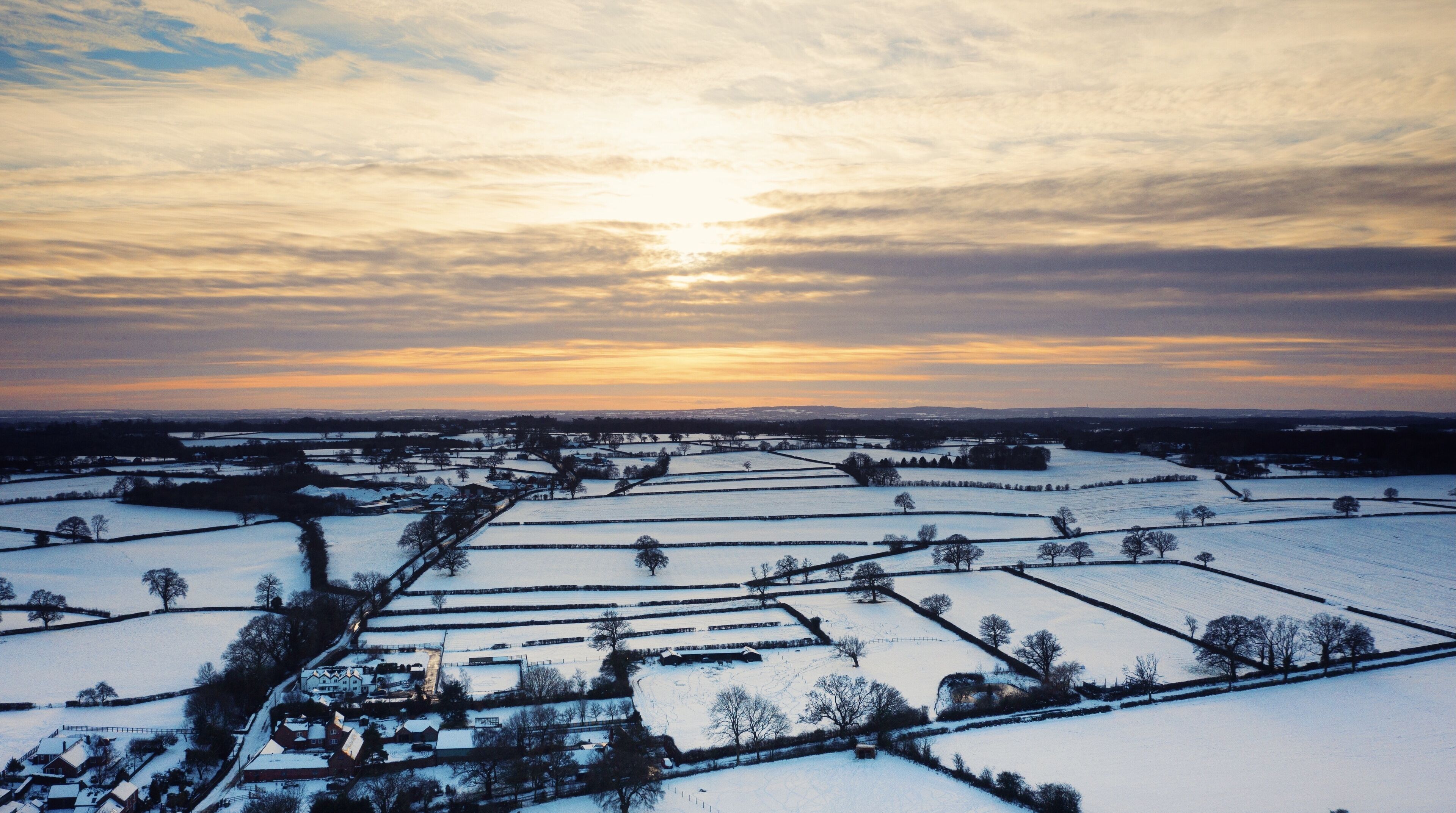 Un paysage rural avec des champs enneigés et un village.