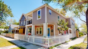 A two-story house with a white picket fence, a covered porch, and a blue door. - Quiet Historic Retreat - 15 minutes from Riverwalk (Wilmington)